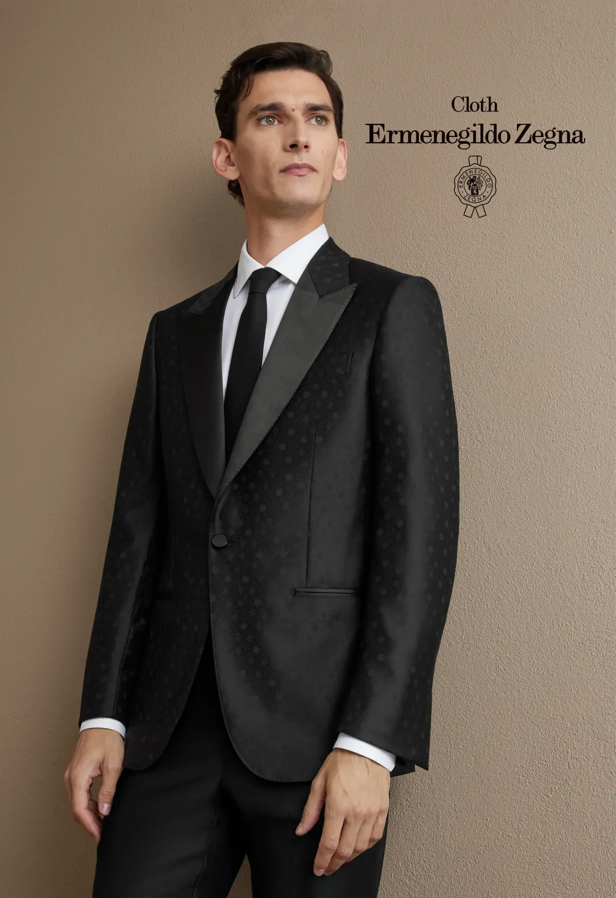 Black jacquard tuxedo with satin peak lapels, white shirt, and black tie—polished, modern eveningwear