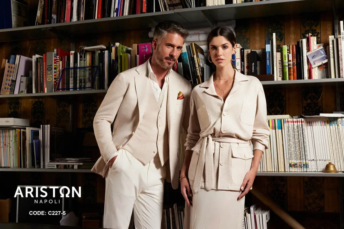 His — cream textured jacket with matching waistcoat, white shirt, ivory trousers, and a saffron pocket square. Hers — belted cream utility-shirt jacket with patch pockets and a matching midi skirt — tailored for elegant occasions